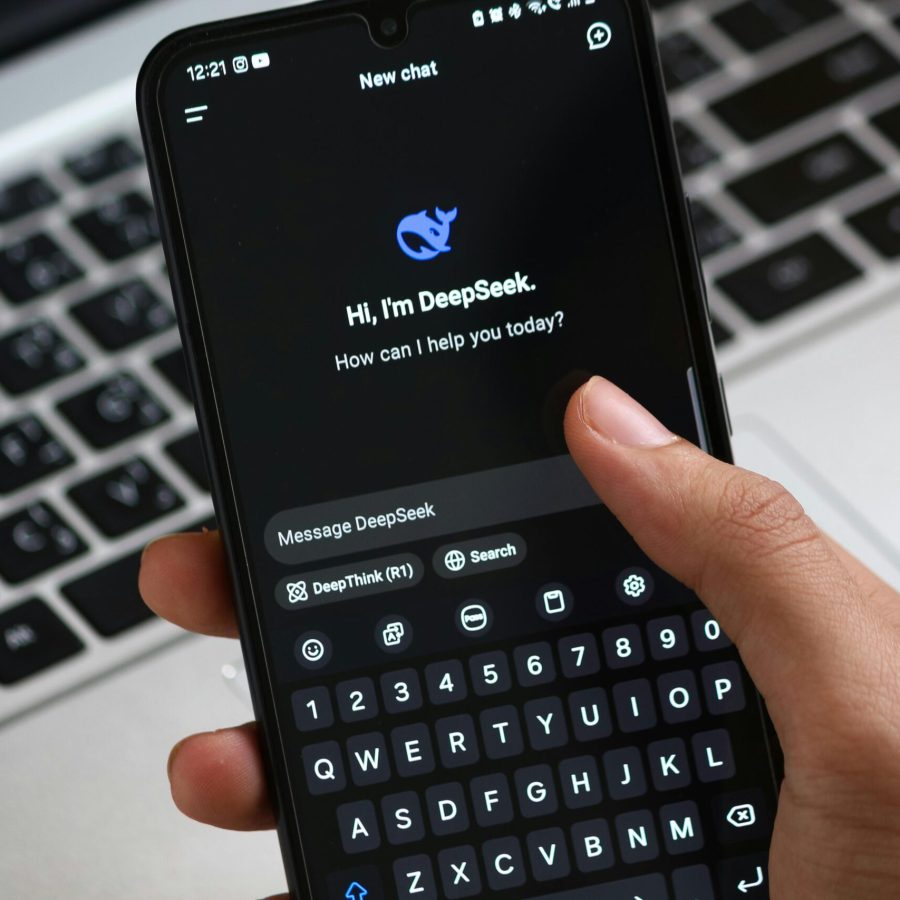 Person interacting with DeepSeek AI chat app on smartphone, focusing on digital innovation and communication.